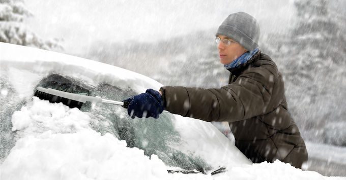 Man wiping his car of snow