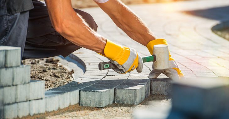 Construction worker laying paver blocks